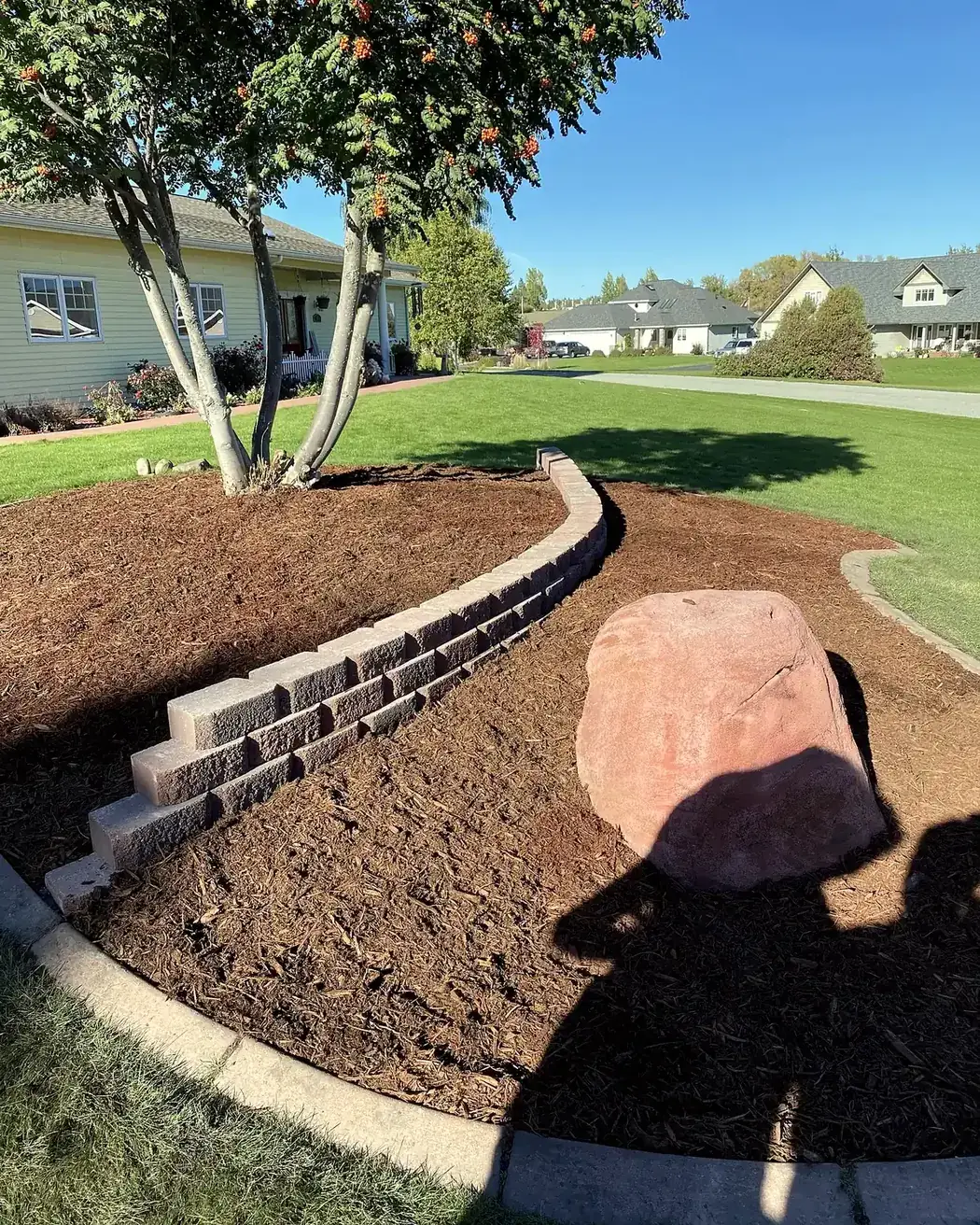 Curved block retaining wall built around a graded slope, Flathead Valley