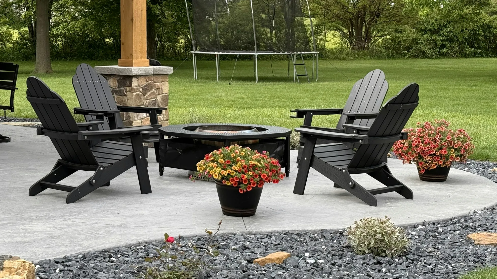 Paver patio with Adirondack chairs and fire pit beside rock beds